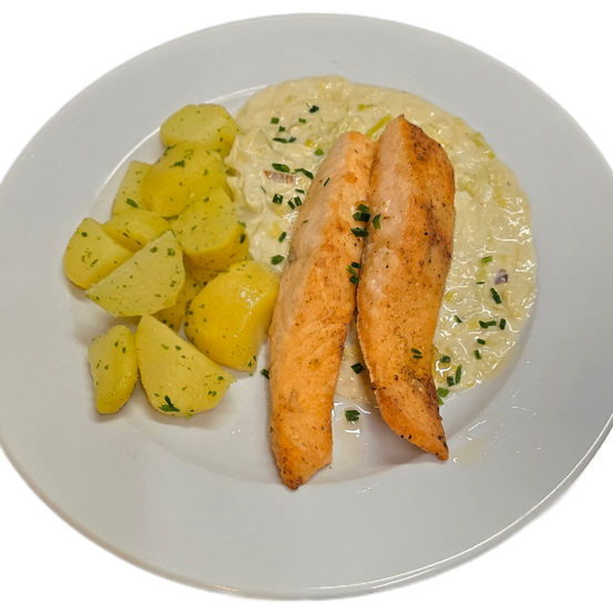 Auf einem weißen Teller befinden sich zwei gegrillte Fischfilets mit cremiger Soße, garniert mit Kräutern, und eine Beilage gekochter gelber Kartoffeln.