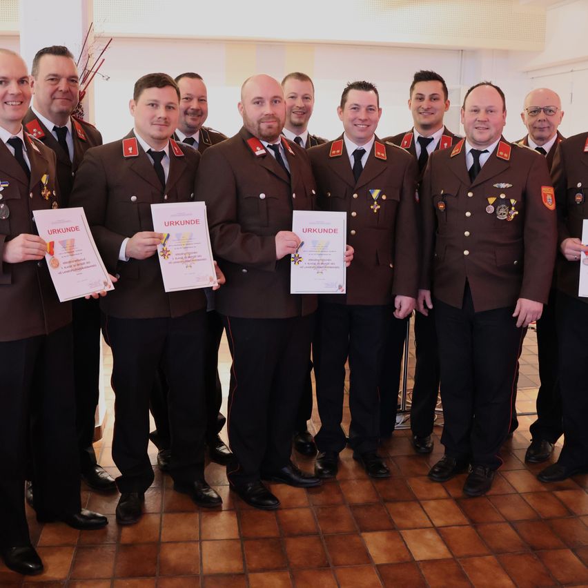 Eine Gruppe von Militäroffizieren, die Urkunden halten und in einem Raum stehen, in Uniformen.