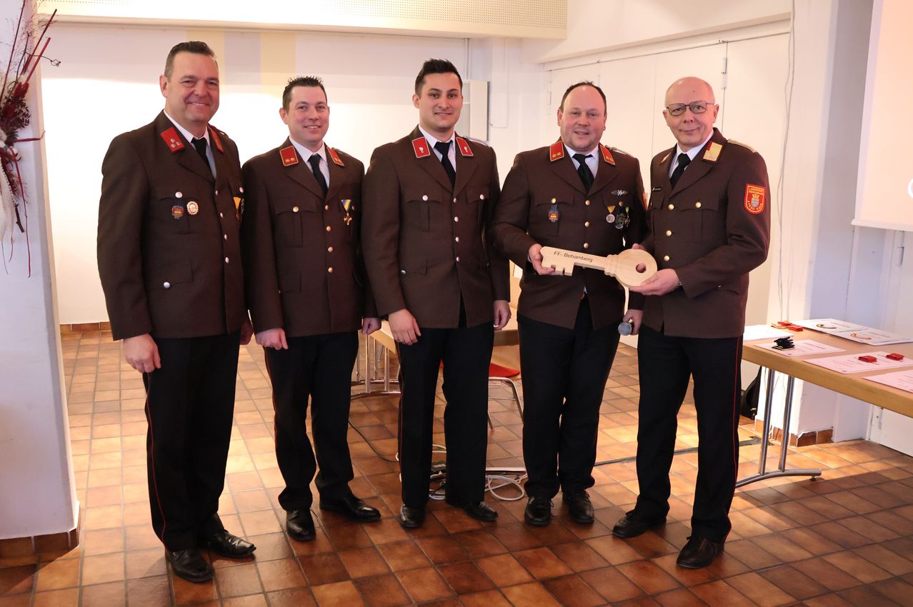 Fünf Männer in Uniform stehen in einem Raum und halten einen Schlüssel mit der Aufschrift FF. Behmenberg. Sie alle scheinen zu lächeln. Der Boden ist gefliest.