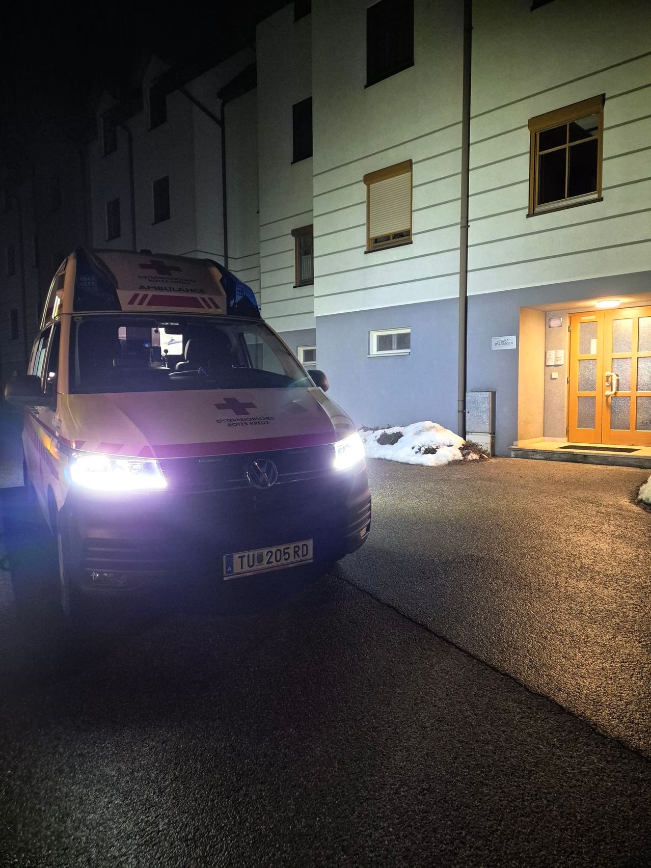 Ein Krankenwagen mit dem Kennzeichen TU 205 RD ist vor einem Gebäude mit Fenstern, einer Tür und Schnee auf dem Boden geparkt.