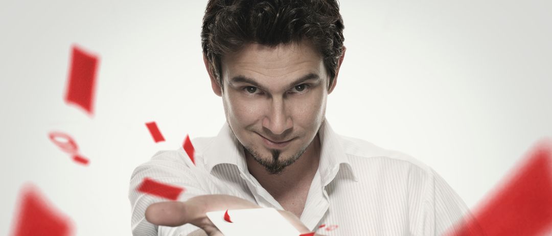 Ein Mann in einem weißen Hemd führt einen Zaubertrick mit einer Karte vor, umgeben von schwebenden roten Karten.