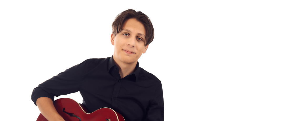 Ein Mann hält eine rote E-Gitarre vor schwarzem Hintergrund. Er trägt ein schwarzes Hemd und hat einen ernsten Gesichtsausdruck.