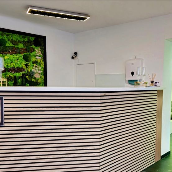 Ein Innenbereich mit einer hölzernen Theke hat eine grüne Wandkunst und eine Kamera an der Wand.