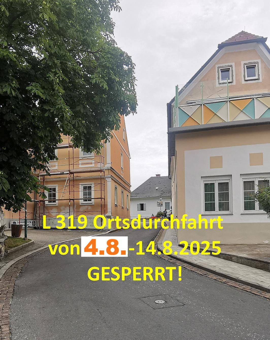Eine Straße mit Gebäuden und Bäumen. Ein Gebäude hat Gerüst und wird renoviert. Ein Schild zeigt an, dass die Straße vom 4. bis 14. August 2025 gesperrt ist.