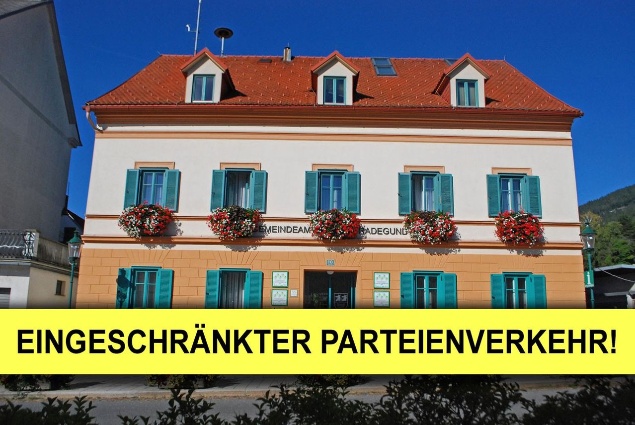 A building with a red roof and multiple windows with green shutters. The building has a banner that says 'Schrankter Parteienver'.