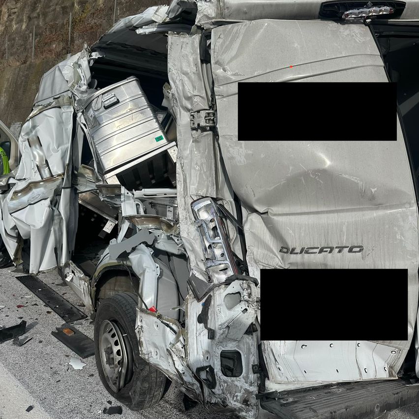 A severely damaged vehicle with its front bumper and hood crumpled. The word 'Ducati' is visible on the bumper. Debris is scattered around.