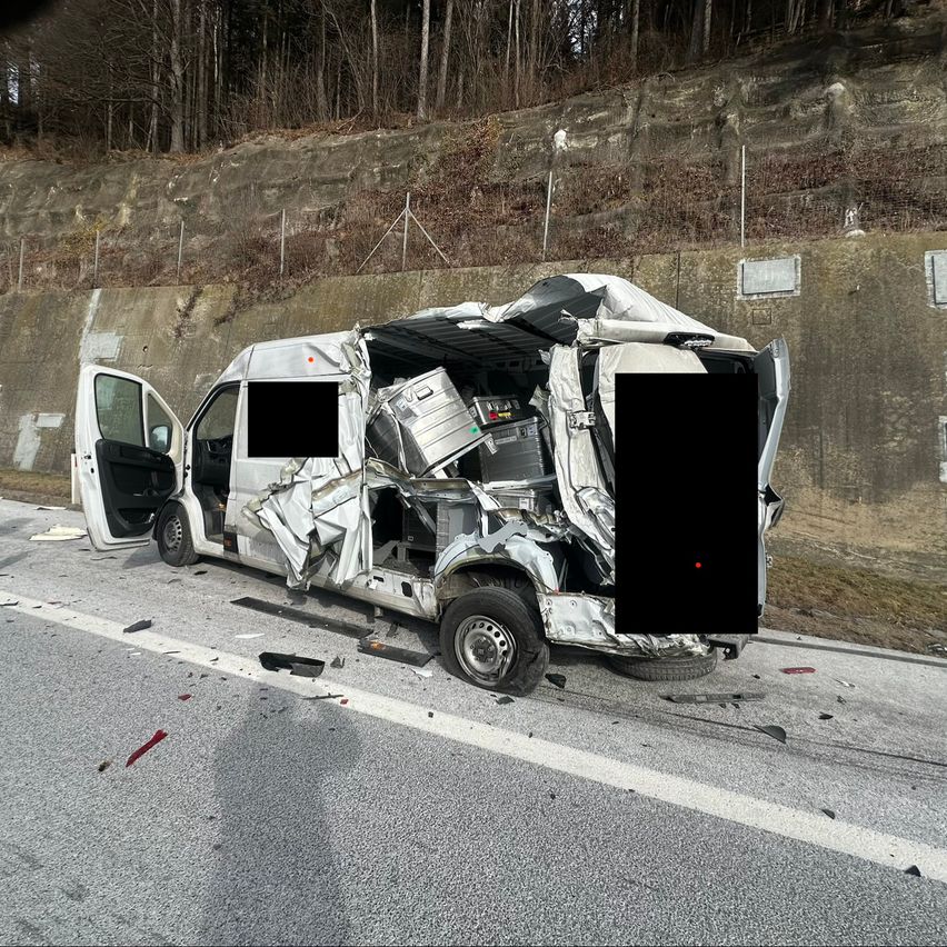 A van with its back doors open and the front severely damaged is parked on the roadside.