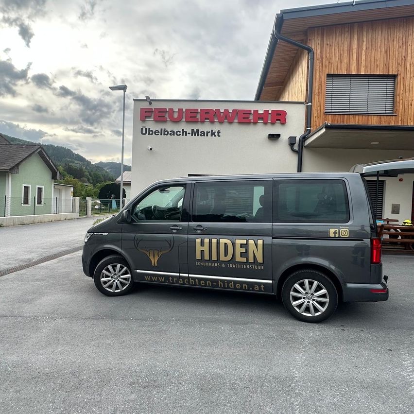 A grey van with the word Hiden on the side parked in front of a building with the words Feuerwehr Ubelbach Markt.