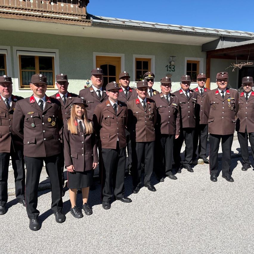 A group of uniformed individuals stands in front of a building with the number 193. A woman is among them.