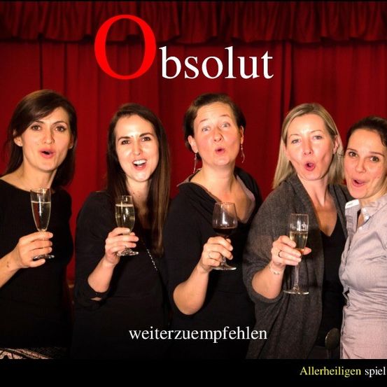 Fünf Frauen stehen vor einem roten Vorhang, alle halten Gläser mit Champagner in der Hand, lächeln und schauen in die Kamera. Das Wort Obsolute steht über ihnen.