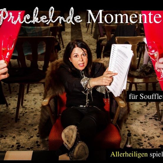 Eine Frau sitzt auf einem Stuhl, hält ein Skript in der Hand und sieht geschockt aus. Hinter ihr halten zwei Hände Weingläser. Die Umgebung scheint ein Theater mit roten Vorhängen zu sein.