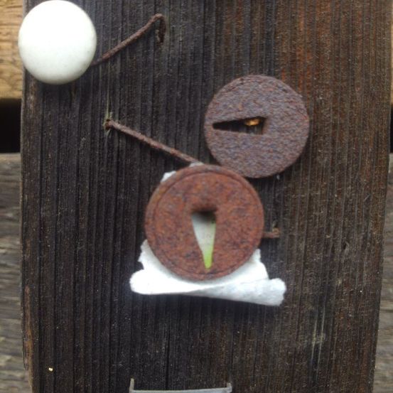 Ein Holzbrett mit einer weißen Kugel, zwei rostigen Metallscheiben und einem angehefteten weißen Material.