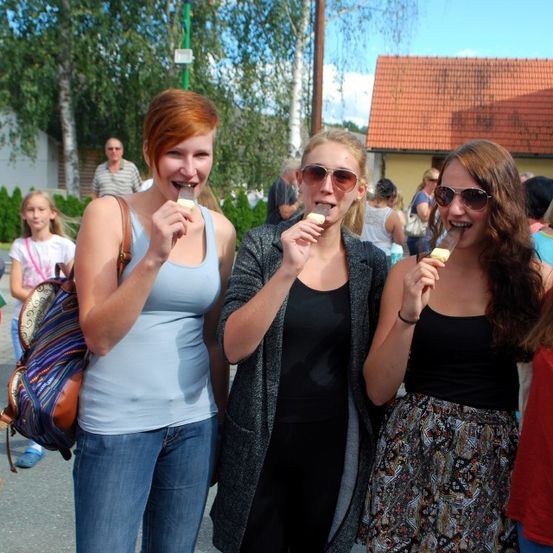 Eine Gruppe lächelnder Frauen mit Eiscreme in den Händen, draußen mit einem Haus und Bäumen im Hintergrund.