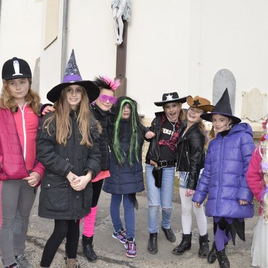 Eine Gruppe junger Mädchen in bunten Kostümen posiert für ein Foto vor einer Kirche.