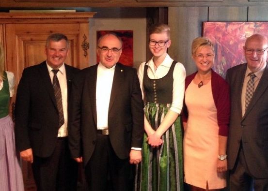 Eine Gruppe von Menschen, darunter Männer und Frauen in formeller Kleidung, stehen zusammen und posieren für ein Foto. Sie scheinen sich bei einer Veranstaltung zu befinden.