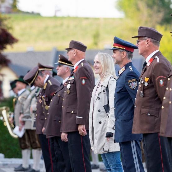 Eine Gruppe von Militäroffizieren und einer Frau in Zivilkleidung steht in einer Reihe, wahrscheinlich bei einer formellen Veranstaltung. Sie tragen alle Mützen, Medaillen und Uniformen.