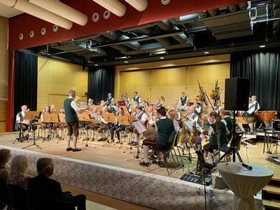 Eine Band spielt auf der Bühne, mit Musikern, die verschiedene Instrumente spielen, während ein Publikum zuschaut.