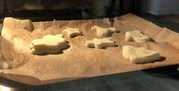 Ein Backblech mit Backpapier enthält mehrere gebackene Kekse in Tier- und Herzform, in einem Ofen.