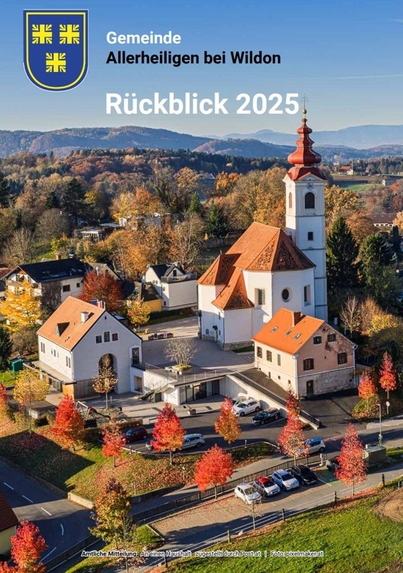 Luftaufnahme eines malerischen Dorfes mit einer Kirche, Häusern und Herbstbäumen. Der Ort liegt vor einer Bergkulisse. Das Bild hat einen Wasserzeichen mit dem Text 'Ruckblick 2025'.