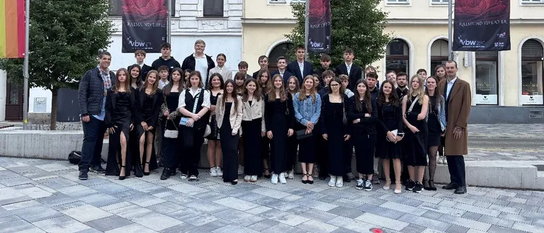 Gruppenfoto von Schülern und Lehrern vor einem Theater mit Phantom der Oper-Bannern.