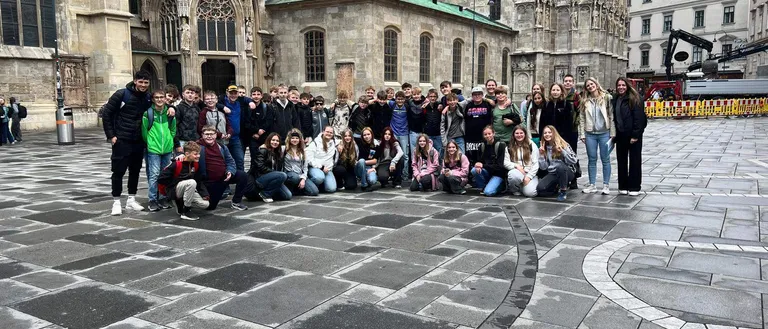 Eine Gruppe von Menschen, einschließlich Schülern, posiert für ein Foto vor einer Kathedrale.