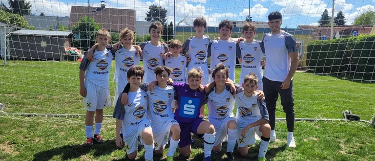 Eine Fußballmannschaft junger Jungen und ihr Trainer posieren für ein Foto vor einem Tor.