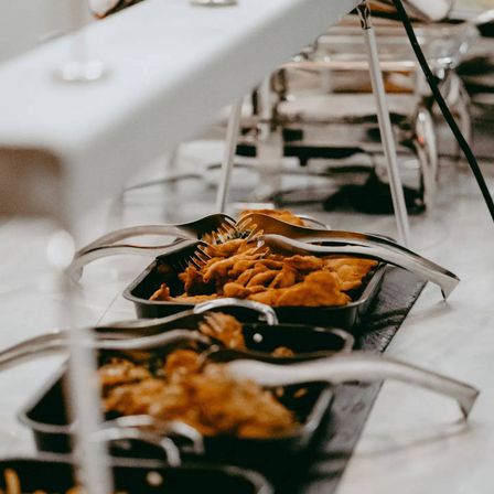 Einige Speisen werden in Schalen mit Gabeln serviert. Die Schalen stehen auf einem Tresen. Der Raum ist gut beleuchtet.