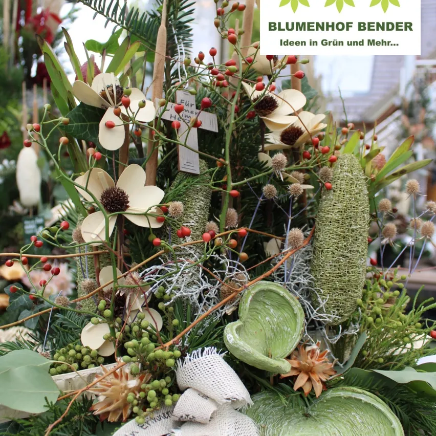 Ein Nahaufnahme einer Blumenarrangement mit weißen Blumen, grünen Blättern und roten Beeren. Das Arrangement ist mit einem weißen Band gebunden und in einem Holzvase platziert.