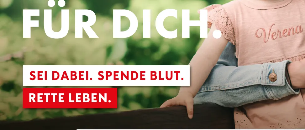 Ein lächelndes Baby mit einem rosa Shirt und dem Wort Verena darauf, auf dem Schoß einer Frau. Der Hintergrund ist unscharrig grün.