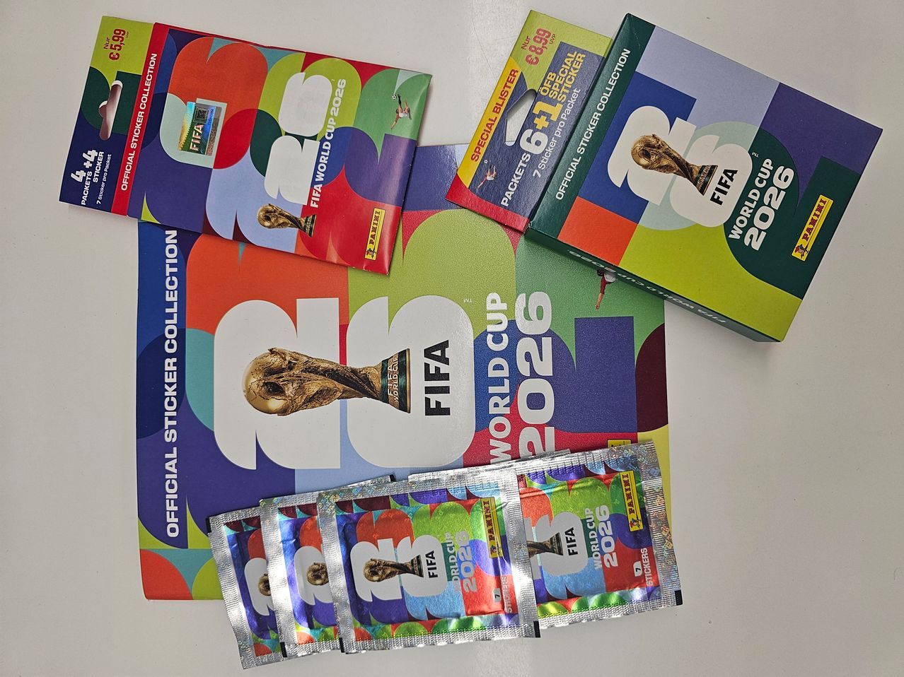 Official FIFA World Cup 2026 sticker collection items on a white surface. Includes packets and a booklet.