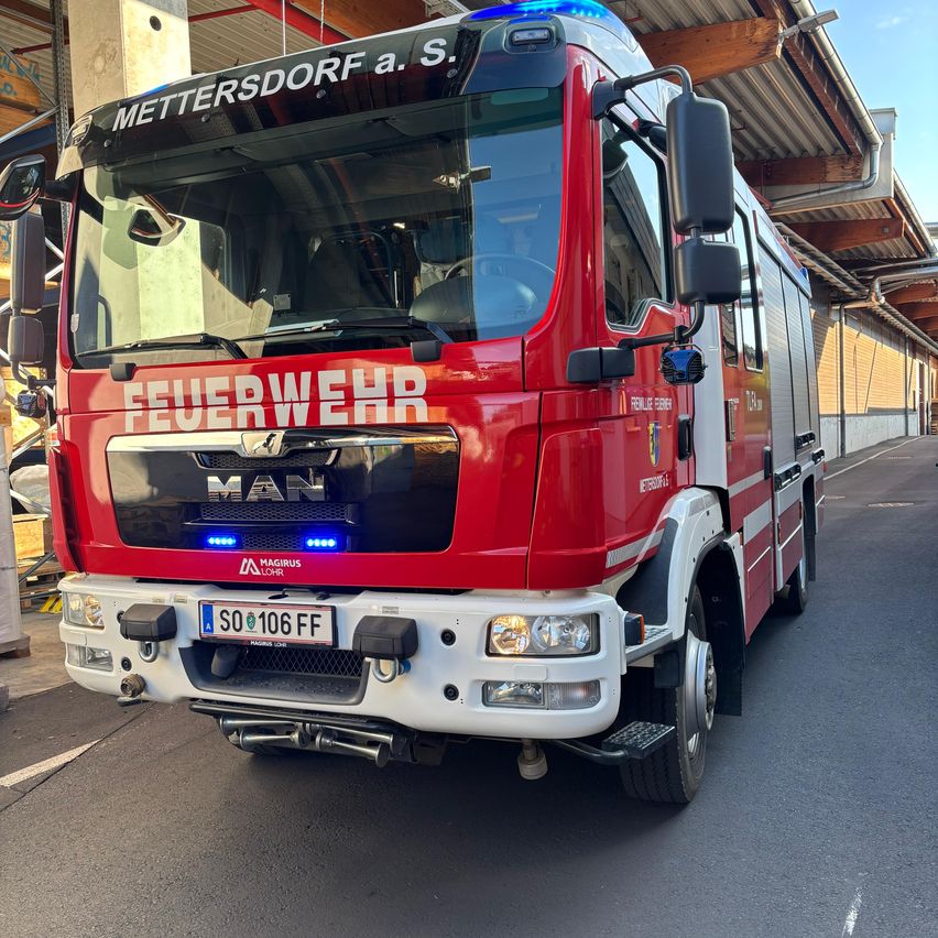 Ein roter Feuerwehrwagen mit 'METTERSDORF A. S.' oben, 'FEUERWEHR' vorne und dem Kennzeichen 'SO 106 FF' steht in einer Garage.