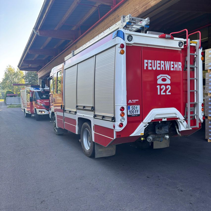Ein rot-weißer Feuerwehrwagen mit der Nummer 122 steht vor einer Feuerwache. Ein weiterer Feuerwehrwagen ist dahinter geparkt.