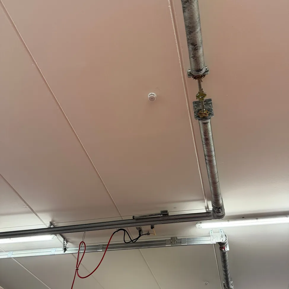 Ein Nahaufnahme einer Decke mit Metallrohren und Drähten.