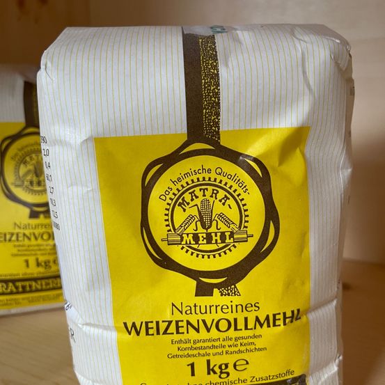 Ein Beutel mit 1 kg reinem Weizenvollmehl, garantiert frei von allen Körnern, Schalen und Verunreinigungen. Der Beutel ist versiegelt und mit einem goldenen Logo und Text beschriftet.