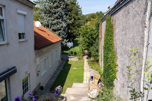 Ein Hinterhof mit einem Rasenbereich, einem Basketballkorb und einem Haus mit rotem Dach.