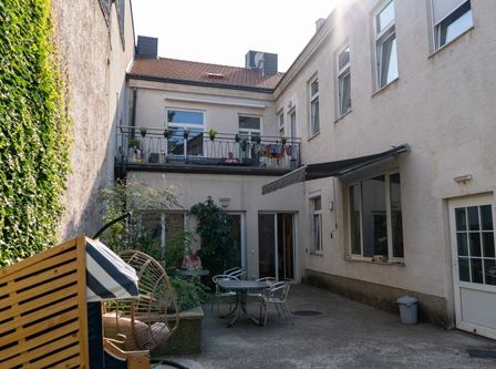 Ein kleiner Innenhof mit einem Gartentisch und Stühlen sowie einer Terrasse mit Pflanzen und Wäsche, die an den Geländern hängen.