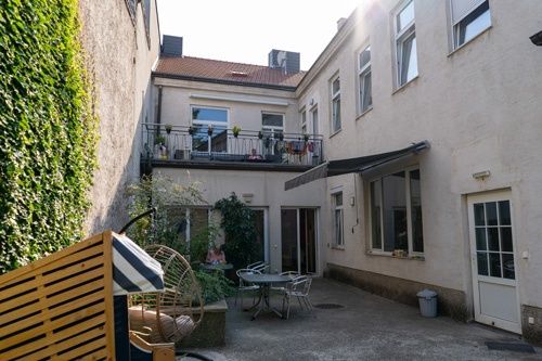 Ein kleiner Innenhof mit einem Gartentisch und Stühlen sowie einer Terrasse mit Pflanzen und Wäsche, die an den Geländern hängen.