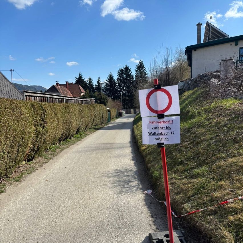 Ein Weg mit einem Schild, das Fahrzeuge verbietet und angibt, dass der Weg nach Waltenbach 17 möglich ist. Das Schild ist an einem roten Pfosten befestigt.