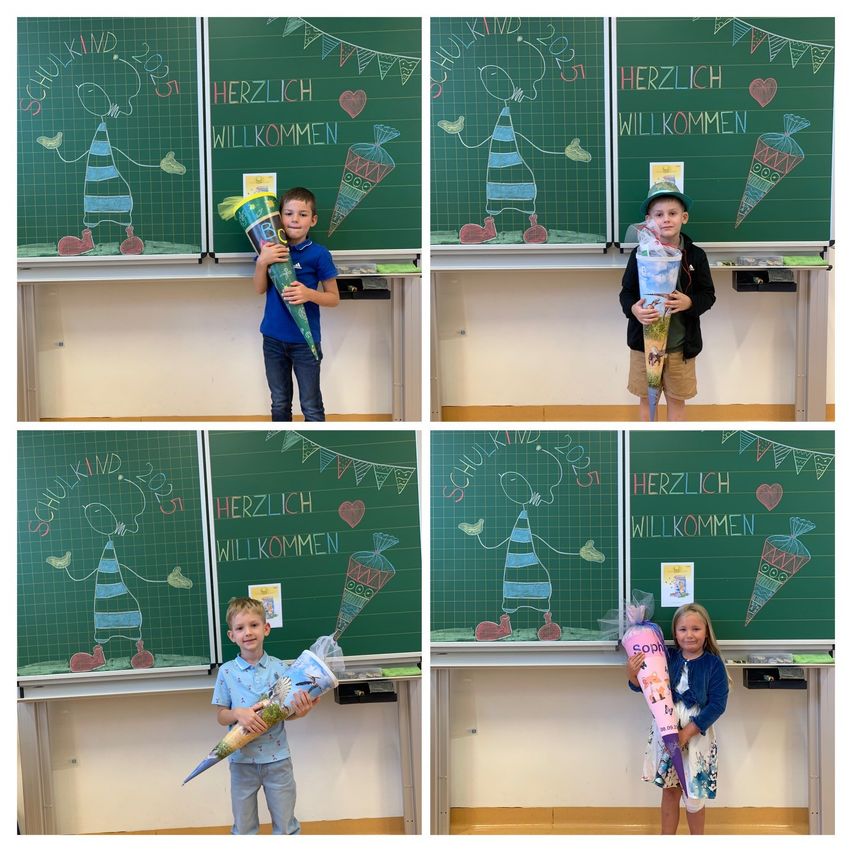 Vier Kinder stehen vor Tafeln mit Blumensträußen. Die Tafeln sind mit Zeichnungen von Kindern und Luftballons dekoriert, und Botschaften wie 'Herzlich willkommen' sind darauf geschrieben. Jedes Kind hat einen Strauß und eine Willkommensbotschaft.
