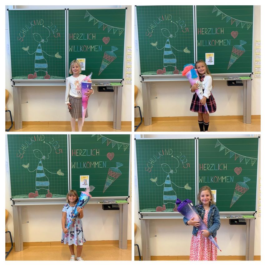 Vier junge Mädchen stehen vor Tafeln und halten Blumensträuße. Die Tafeln haben farbenfrohe Zeichnungen und Texte, einschließlich 'Herzlich willkommen'. Die Mädchen sind in verschiedenen Posen und Outfits.