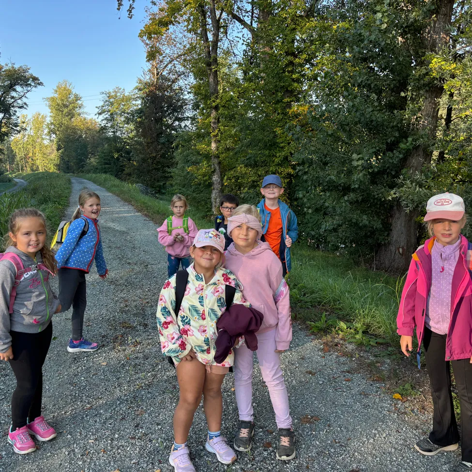 Eine Gruppe von Kindern steht auf einem Kiesweg im Wald und lächelt und posiert für ein Foto.