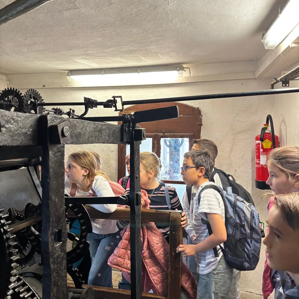 Eine Gruppe von Kindern versammelt sich um ein großes mechanisches Gerät in einem Raum.