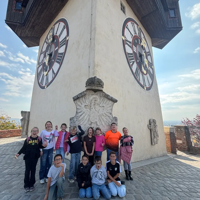 Eine Gruppe von Menschen posiert für ein Foto vor einem Uhrturm.