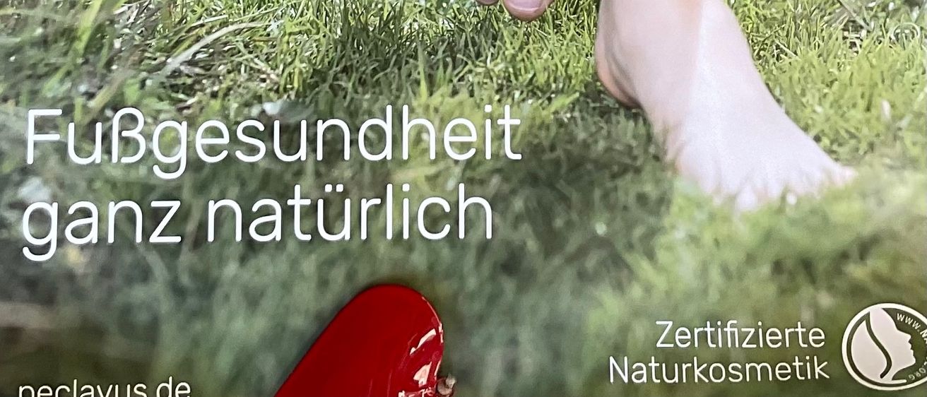 Die Beine einer Person befinden sich auf einem Grasfeld. Die Person ist barfuß. Der Text lautet FuBgesundheit ganz naturlich.