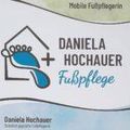 Das Logo für einen mobilen Fußpflegedienst zeigt ein Haus mit einem Fußabdruck, einem Vogel und dem Text Daniela Hochauer Fußpflege. Das Logo hat eine blau-weiße Farbgebung.