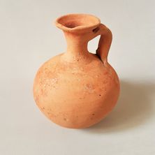 Eine alte Terrakotta-Krug mit einem Henkel auf weißem Hintergrund, der Anzeichen von Alter mit weißen Flecken aufweist.