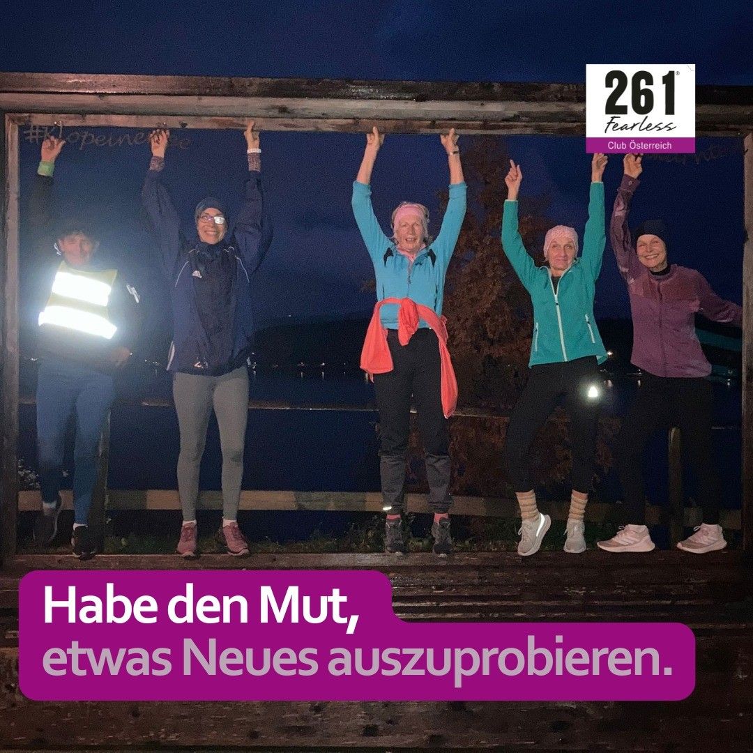 Fünf Frauen posieren nachts auf einer Holzkonstruktion für ein Foto, wobei eine Person eine Lampe hält. Das Bild hat einen Wasserzeichen von '261 Fearless Club Osterreich'. Der Textüberlagerung lautet 'Habe den Mut, etwas Neues auszuprobieren.'