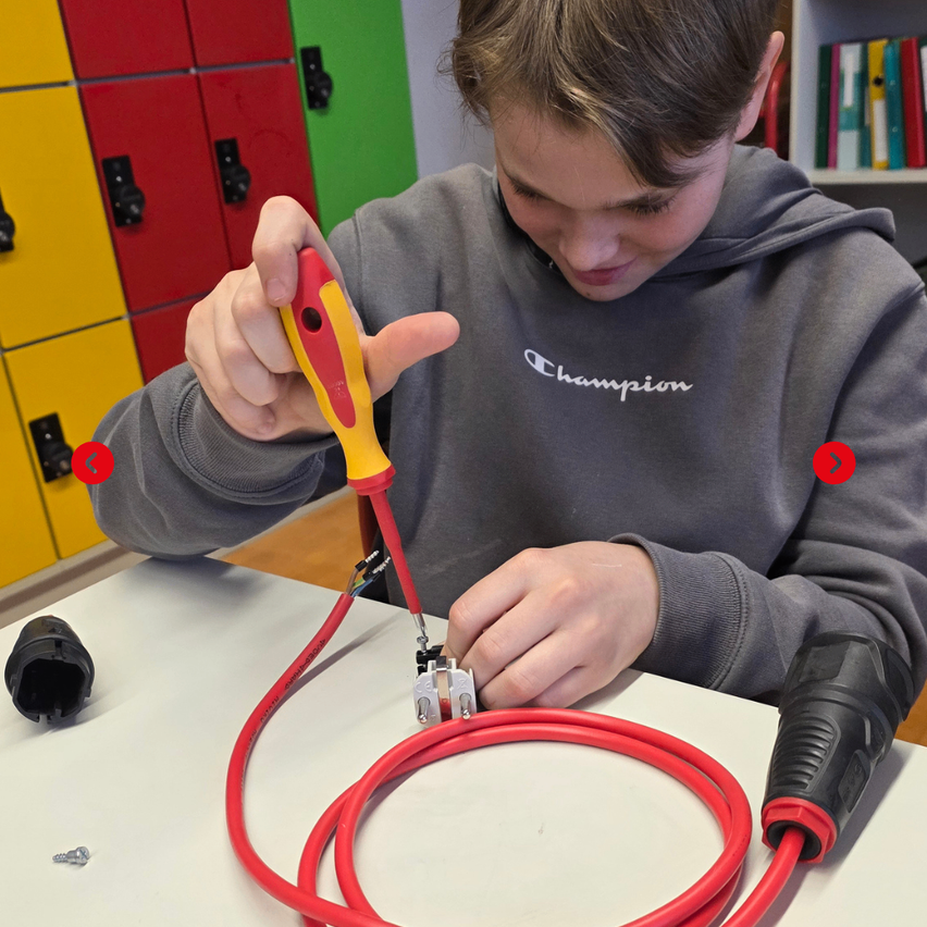 Ein junger Junge benutzt ein Werkzeug, um Kabel auf einem Tisch zu verbinden und konzentriert sich dabei auf seine Aufgabe.