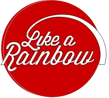 Ein rotes kreisförmiges Logo mit weißem Text, der 'Wie ein Regenbogen' lautet. Der Text ist in einer verspielten, kursiven Schrift gehalten.