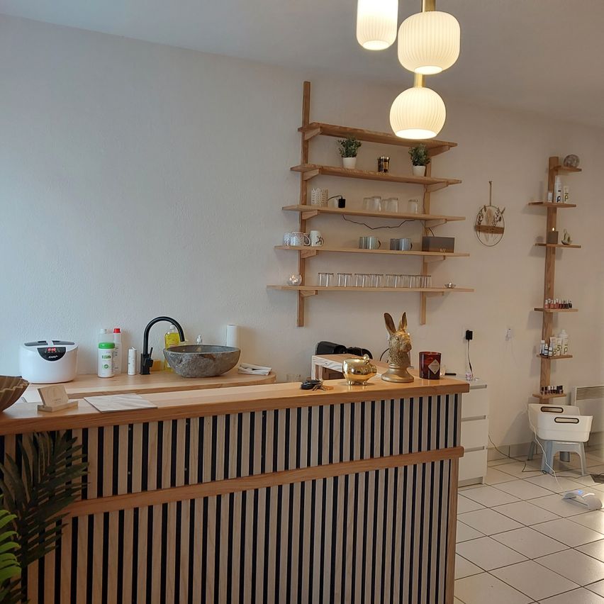 Ein moderner Empfangsbereich mit einer Holztheke, Regalen mit Gegenständen, einem Waschbecken und einem Wasserhahn. Er hat ein sauberes und organisiertes Erscheinungsbild.